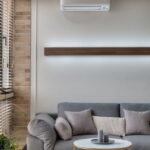A stylish living room featuring a gray sofa, air conditioner, and minimalist decor for a cozy atmosphere.